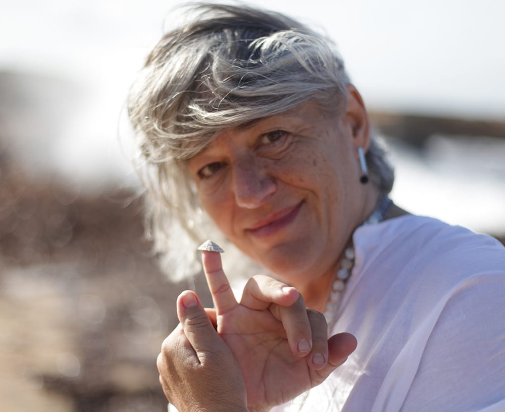 Anna Roca terapeuta natural mostrando una concha en el dedo como símbolo de conexión con la naturaleza